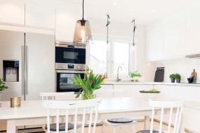 Modern white kitchen space with stainless steel appliances and accessories